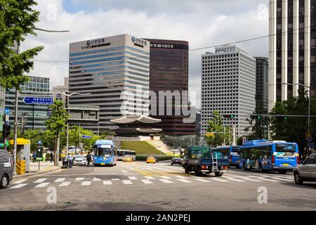Seoul, South Korea - June 16 2017: Buses and cars drive in front of the Namdaemun Gate which contrasts with modern office building in Seoul downtown d Stock Photo