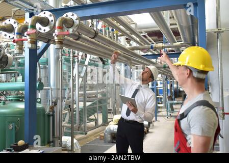 businessman and worker meeting in a factory - maintenance and repair of the industrial plant Stock Photo