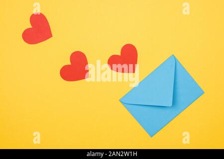 three decorative red hearts and envelope on yellow background Stock Photo