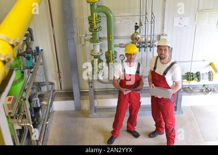 Mechanics repair a machine in a modern industrial plant - profession and teamwork - portrait group workman Stock Photo