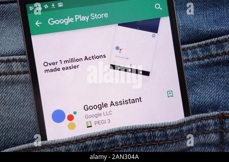 Google Assistant app on Google Play Store website displayed on smartphone hidden in jeans pocket Stock Photo