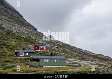 Traditional norwegian wooden mountain huts cabin at Troll path Trollstigen, Norway. Cloudy white sky and rocky hills travel scenery. Stock Photo