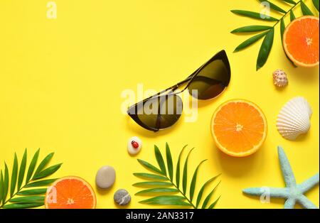 Tropical Summer Beach Background. Palm Trees Branches, tarfish, seashell, sunglasses and orange on yellow summer background. Travel. Summer concept. C Stock Photo