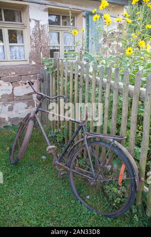 Old rusty bicycle leaning against wooden fence Stock Photo