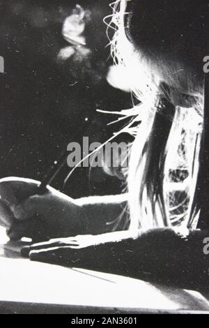 Fine seventies black and white extreme photography of girl writing at a desk with backlighting Stock Photo