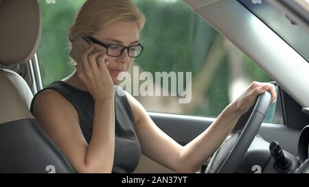 Angry business woman quarreling with husband on smartphone in car, stress Stock Photo