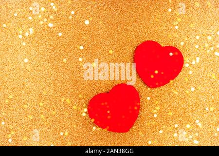 Two red wooden hearts on gold sparkles background. Stock Photo