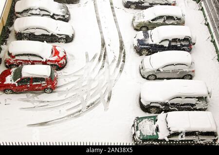 Car tracks in parking lot during snowstorm Stock Photo