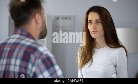 Exhausted lady suffering from domestic violence, arguing with aggressive husband Stock Photo