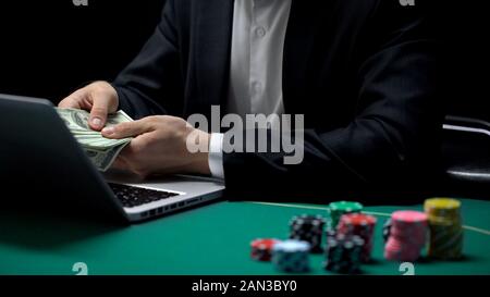 Online casino player counting dollars winning prize money in poker, gambling Stock Photo