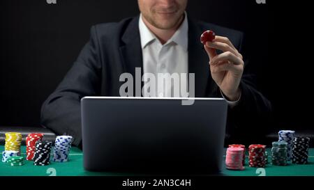 Smiling businessman confidently placing bet online on laptop, casino web site Stock Photo