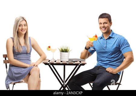 Couple sitting at a table with cocktails isolated on white background Stock Photo