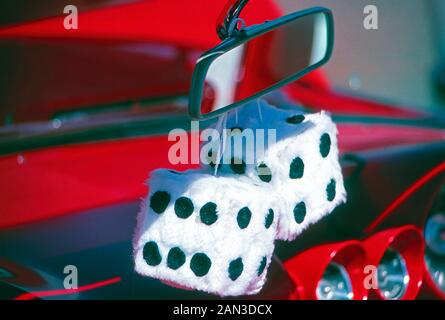 Fuzzy dice hanging from the rear view mirror of a vintage car Stock Photo