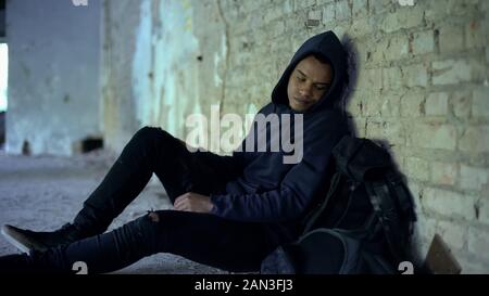 Afro-american teenager hiding from bullying in abandoned building, racism Stock Photo