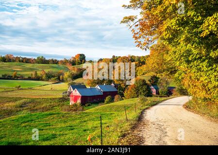 Traditional farm along a gravel road in a rolling rural landscape in New England in autumn. Beautiful fall foliage. Stock Photo