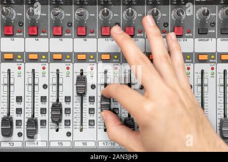Close-up of a mixing console, hand equalizing audio channels. Professional recording studio. Working in recording studio . Stock Photo