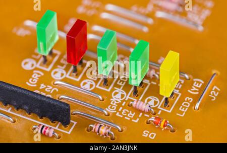 Colored rectangular light-emitting diodes in row on printed circuit board in detail. Close-up of green, red and yellow plastic LED lights on beige PCB. Stock Photo