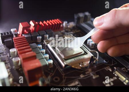 Application of thermal paste on the laptop processor chip for high-quality cooling. Spreading thermal compound to iprove cooling performance. Upgrade Stock Photo