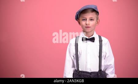 Little boy in vintage clothes looking into camera, isolated on pink background Stock Photo