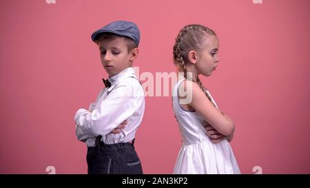 Little male looking at offended young girlfriend, standing back to each other Stock Photo