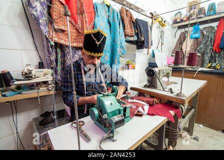 March 5, 2019: An elderly tailor man in a using a sewing machine. Yazd, Iran Stock Photo