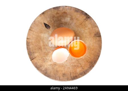 Brown eggs on a wooden chopping board There is a yolk in the egg shell. The brown egg has a drop of water because it is removing from the refrigerator Stock Photo