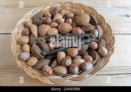 Mixed nuts, Walnut, Brazil and Hazel nuts, in wicker basket with vintage nutcracker. Stock Photo