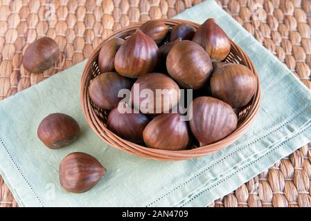 Sweet Chestnuts (Castanea sativa) in small wicker basket Stock Photo