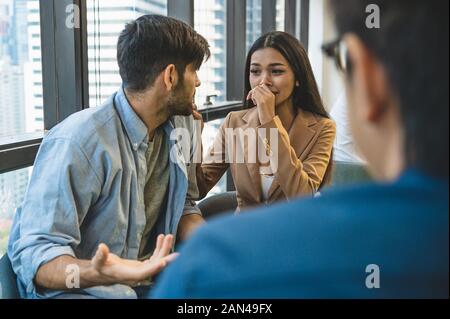Psychotherapist inquiring about symptoms occurring within mind from couple patients with mental health problems. Group psychotherapy for support and h Stock Photo