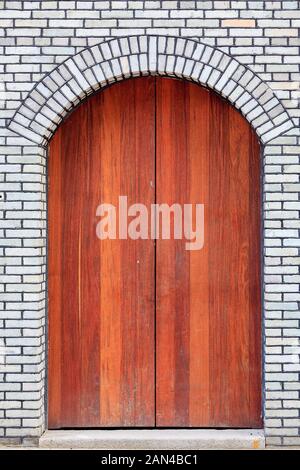 The traditional  wooden arched door and brick wall,which has the style of typical architecture of southern China in the Late Qing Dynasty . Three lane Stock Photo