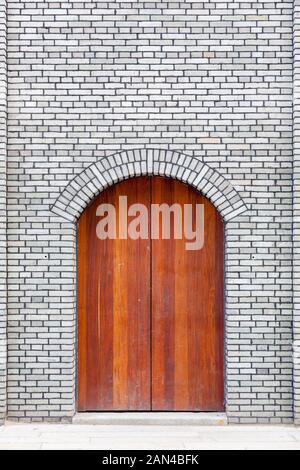 The traditional  wooden arched door and brick wall,which has the style of typical architecture of southern China in the Late Qing Dynasty . Three lane Stock Photo