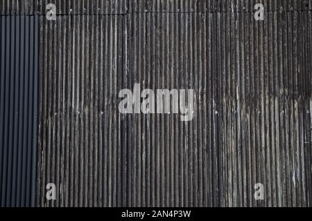 Black color old rusty wavy metal plate wall background Stock Photo