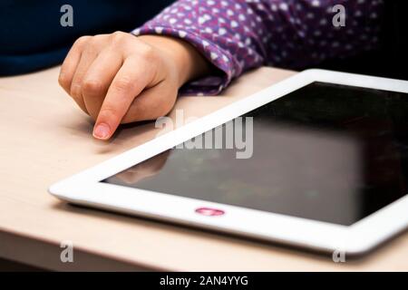 Close up front view of a little girl's hand using and white tablet with a privacy camera cover, during the day time Stock Photo
