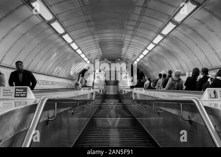 A lot of people are going downwards at the London Tube. Only a couple of people are going up. Stock Photo