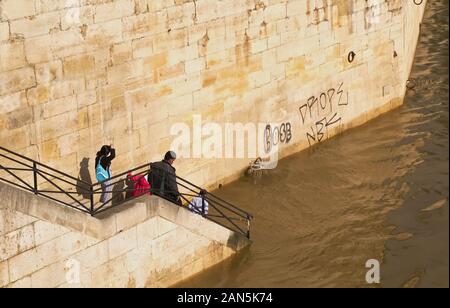 Paris, Ile de France / France - June 16, 2016: Indian family investigate the high floodwaters of the River Seine from a staircase formerly leading dow Stock Photo