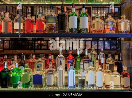 Selection of colorful alcohol bottles on shelves on display at a bar in New York, United States of America, all logos and labels removed