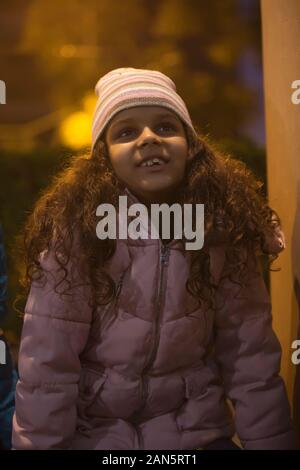 Young girl wearing a beanie looking up at the sky. (Children) Stock Photo