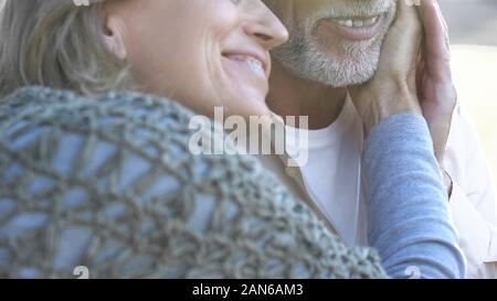 Happy retired couple enjoying romantic date outdoors, woman touching male face Stock Photo
