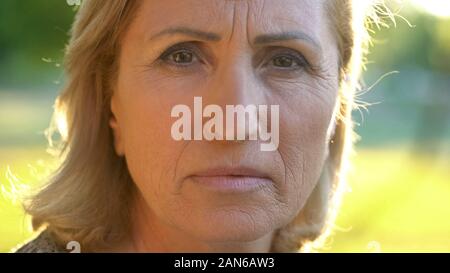 Mature wrinkled grandmother looking into camera, fear for future, pension Stock Photo