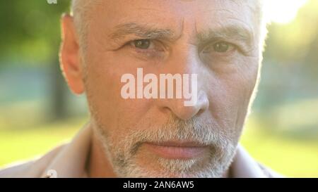 Bearded man in his 70s thinking about future and looking into camera, closeup Stock Photo
