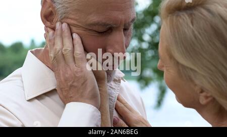 Beautiful aged lady caring about her handsome husband, love and tenderness Stock Photo