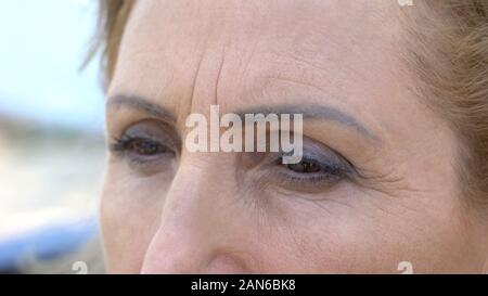 Sad senior woman looking in distance, eyes close up, feeling homesickness Stock Photo