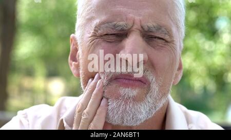 Retired man suffering from toothache, discomfort with implants, dental care Stock Photo