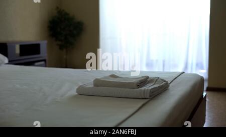 Clean hotel room after housekeeping with fragrant snow white towels on bed Stock Photo