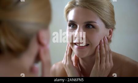Middle aged woman satisfied with face condition after beauty therapist visit Stock Photo