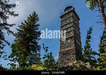 Pajndl, Nejdek / Czech Republic - September 15 2019: View of a stone lookout tower made of granite standing on a hill surrounded with trees. Sunny day. Stock Photo