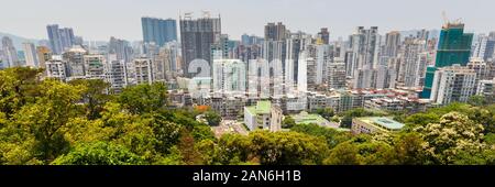 View of Macao skyline with residential / apartment buidlings. In the foreground green trees of Guia Park. Urban landscape / panorama of an asian city. Stock Photo
