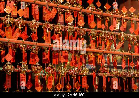 Red colored prayer cards at A-Ma temple. All lined up in rows and hanging on bars. The cards are artistically decorated with bells. Stock Photo