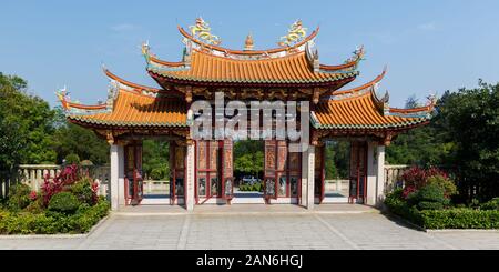 View on entrance gate to A-Ma Cultural Village: Three decorated doors, two golden colored dragons & an orange colored, curved roof (asian temple gate) Stock Photo