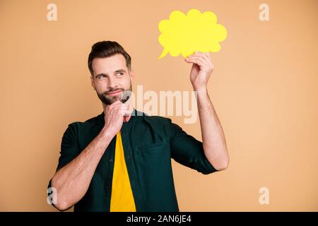 Photo of attractive nice guy holding hand paper cloud thinking over dialogue answer creative person arm on chin tricky sly mood wear casual hipster Stock Photo